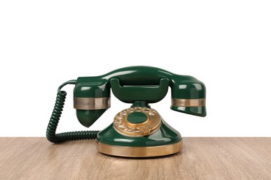 Photo of Green vintage corded telephone on wooden table against light background