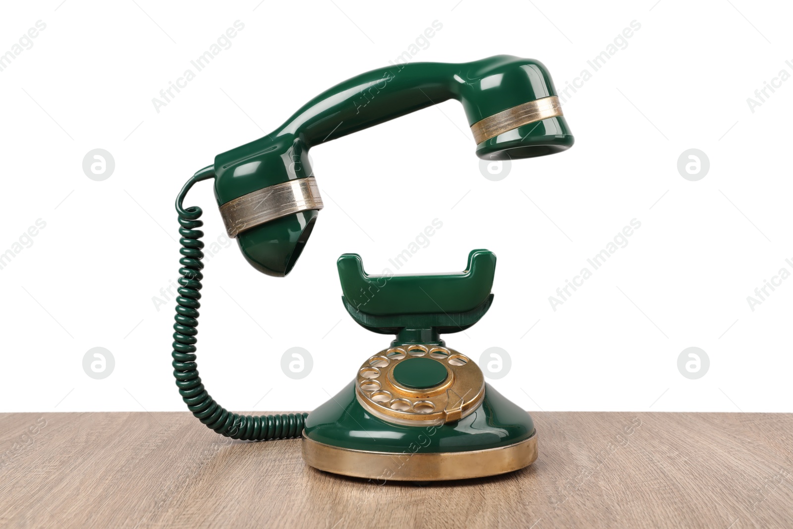 Photo of Green vintage corded telephone on wooden table against light background