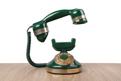 Green vintage corded telephone on wooden table against light background