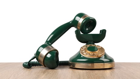 Photo of Green vintage corded telephone on wooden table against light background