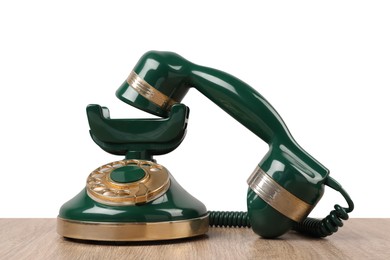 Green vintage corded telephone on wooden table against light background