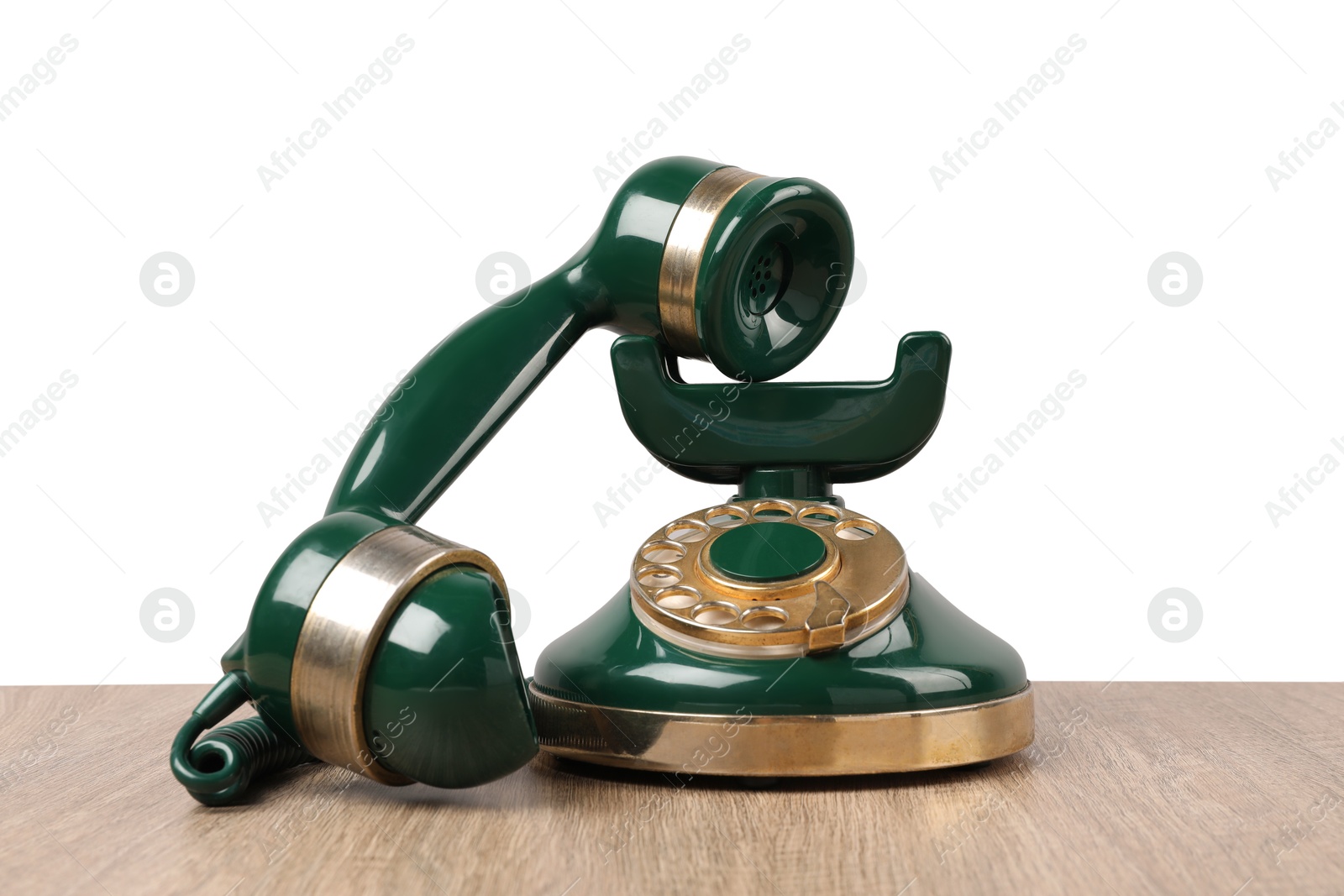 Photo of Green vintage corded telephone on wooden table against light background