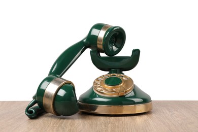 Green vintage corded telephone on wooden table against light background