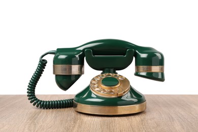 Photo of Green vintage corded telephone on wooden table against light background