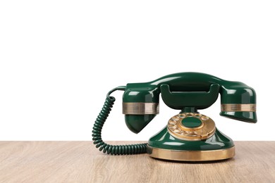 Photo of Green vintage corded telephone on wooden table against light background, space for text