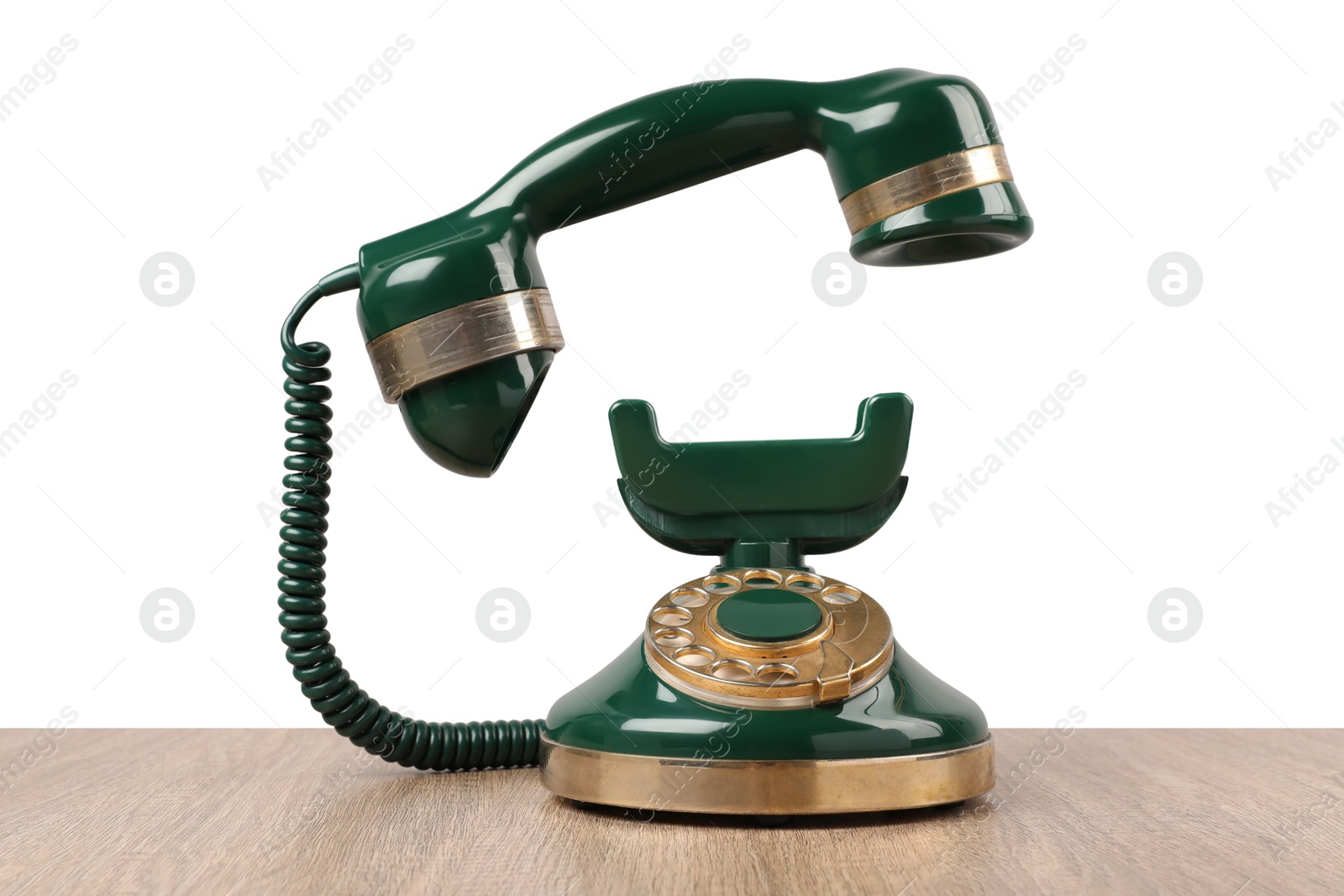 Photo of Green vintage corded telephone on wooden table against light background