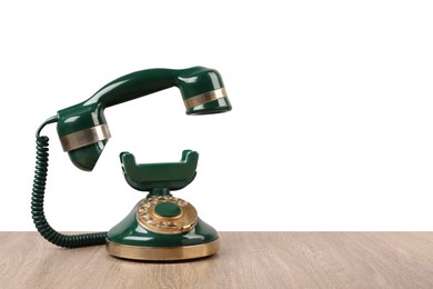 Photo of Green vintage corded telephone on wooden table against light background, space for text