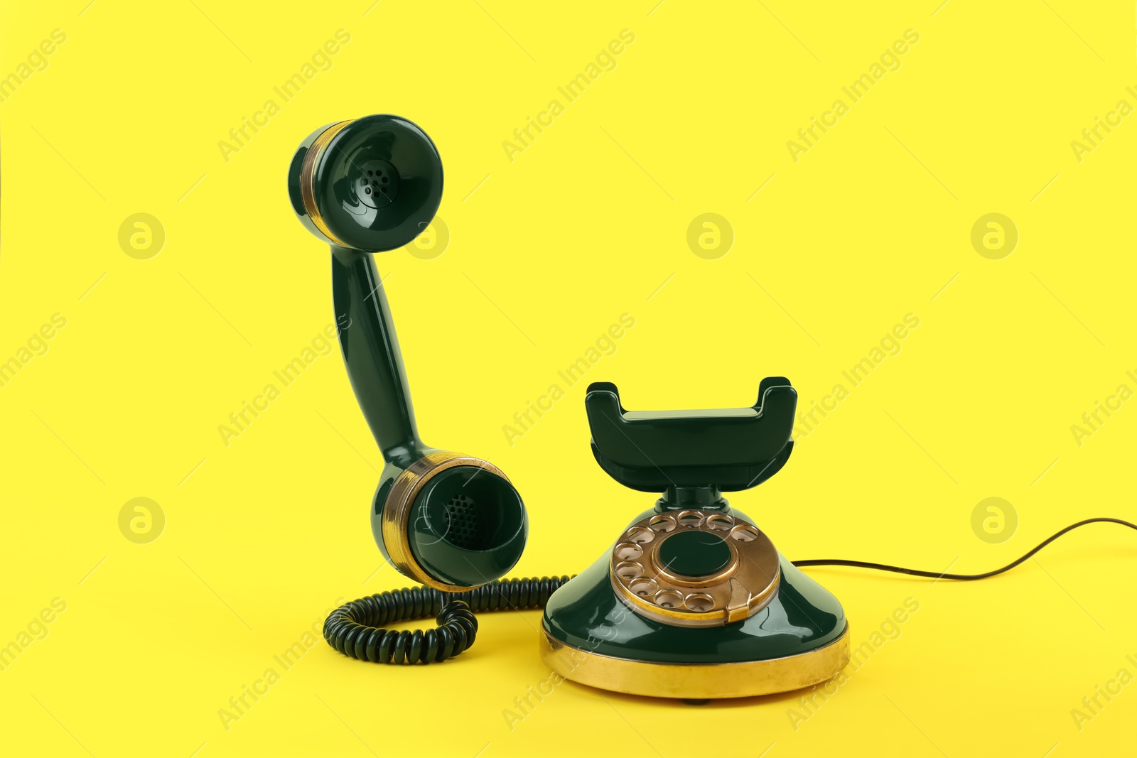 Photo of Green vintage corded telephone on yellow background