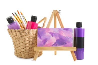 Acrylic paints of different colors with brushes and abstract picture on small easel against white background