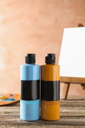 Photo of Acrylic paints of different colors in bottles on wooden table