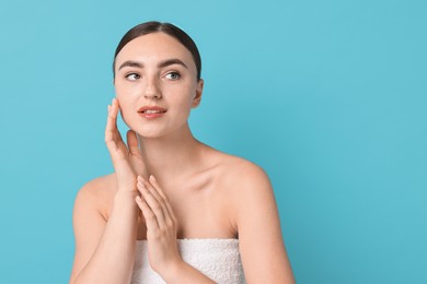 Beautiful young woman with healthy skin on light blue background, space for text