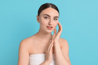 Beautiful young woman with healthy skin on light blue background