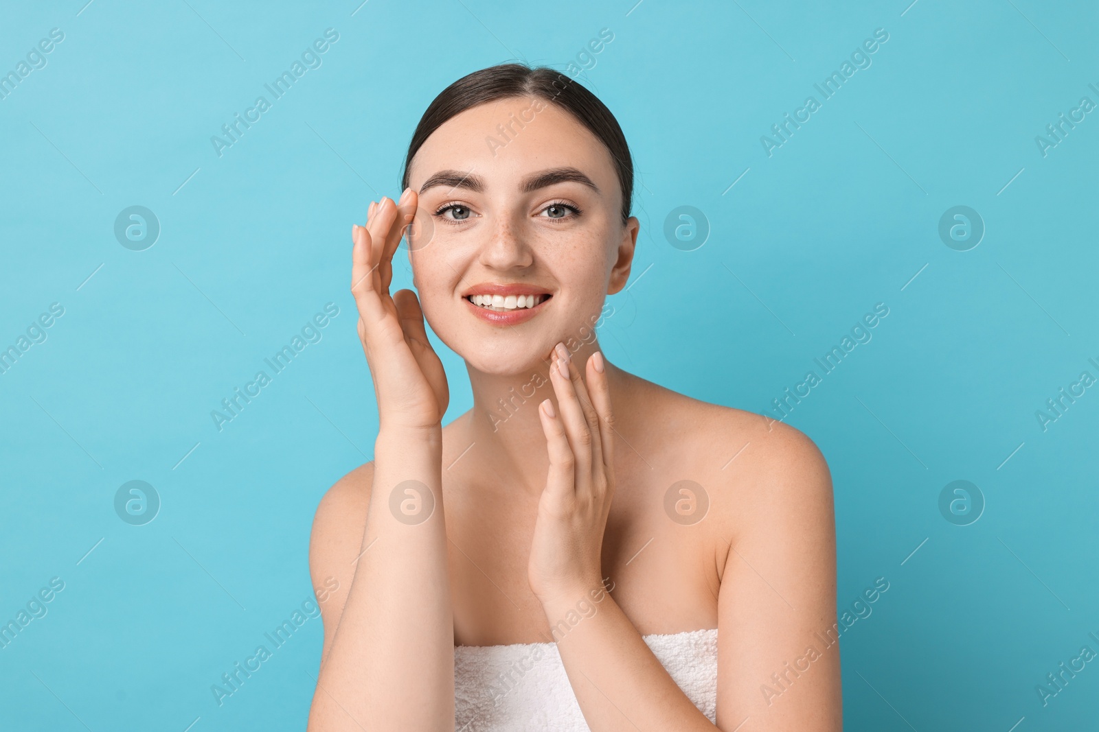 Photo of Face massage. Beautiful young woman with healthy skin on light blue background