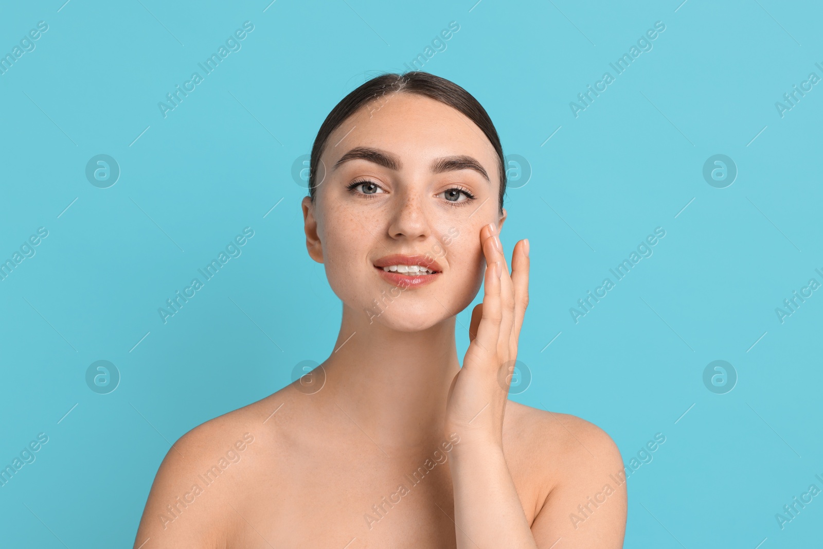 Photo of Face massage. Beautiful young woman with healthy skin on light blue background