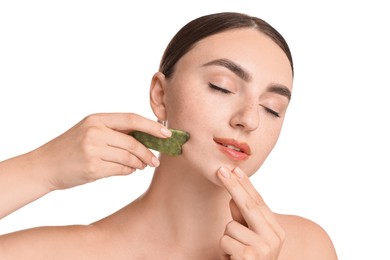 Photo of Beautiful young woman doing facial massage with gua sha tool on white background