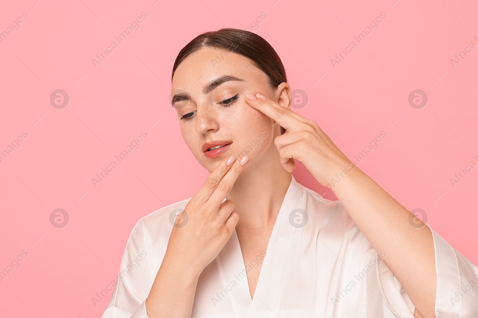 Photo of Beautiful young woman doing facial massage on pink background