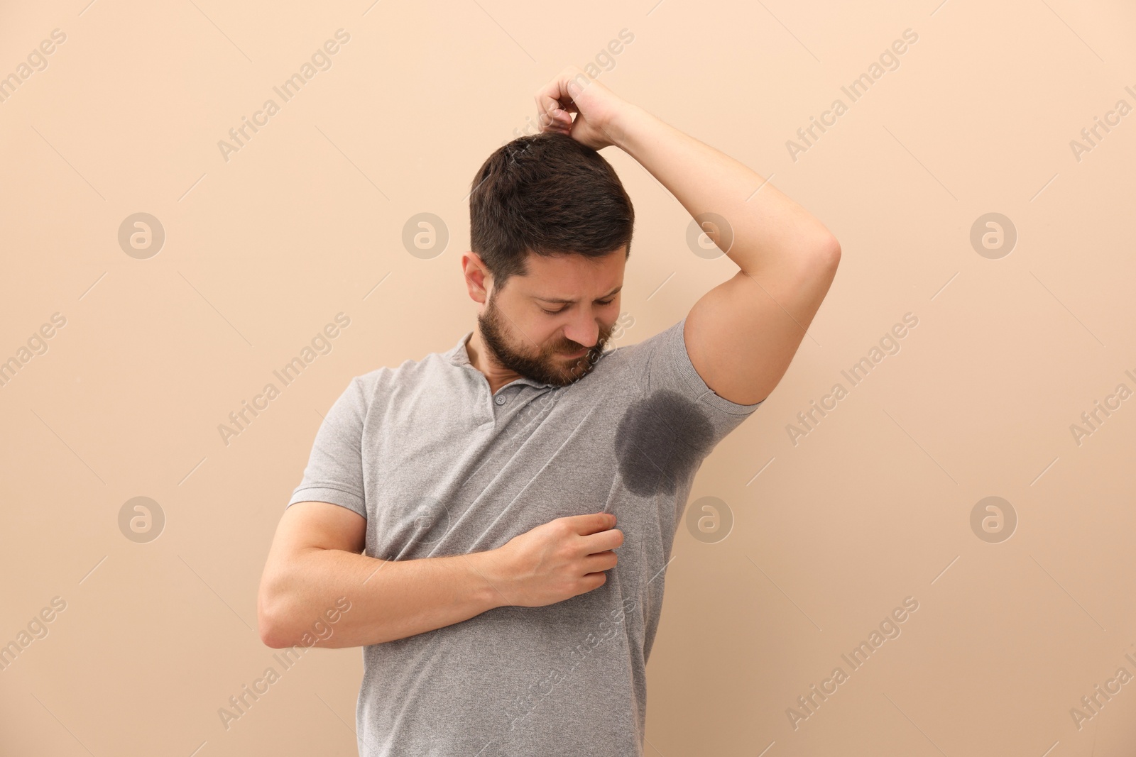 Photo of Man in t-shirt before using deodorant on beige background