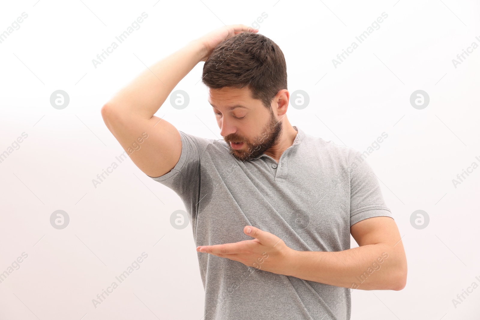 Photo of Emotional man in t-shirt before using deodorant on white background