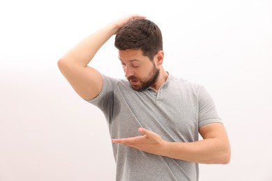 Emotional man in t-shirt before using deodorant on white background