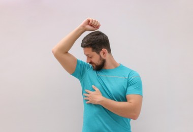 Handsome man after using deodorant on white background