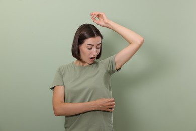 Photo of Emotional woman in t-shirt before using deodorant on green background