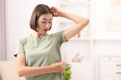 Emotional woman in t-shirt before using deodorant at home