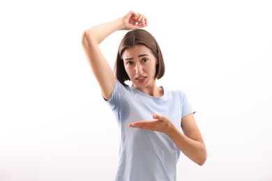 Emotional woman in t-shirt before using deodorant on white background