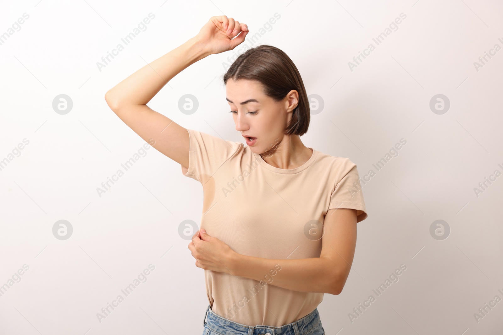 Photo of Emotional woman in t-shirt before using deodorant on white background