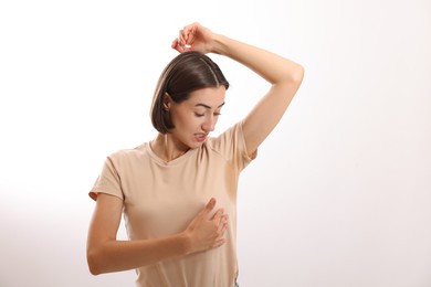 Emotional woman in t-shirt before using deodorant on white background