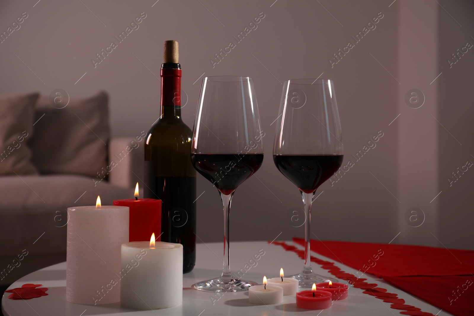 Photo of Burning candles, wine and paper hearts on table indoors