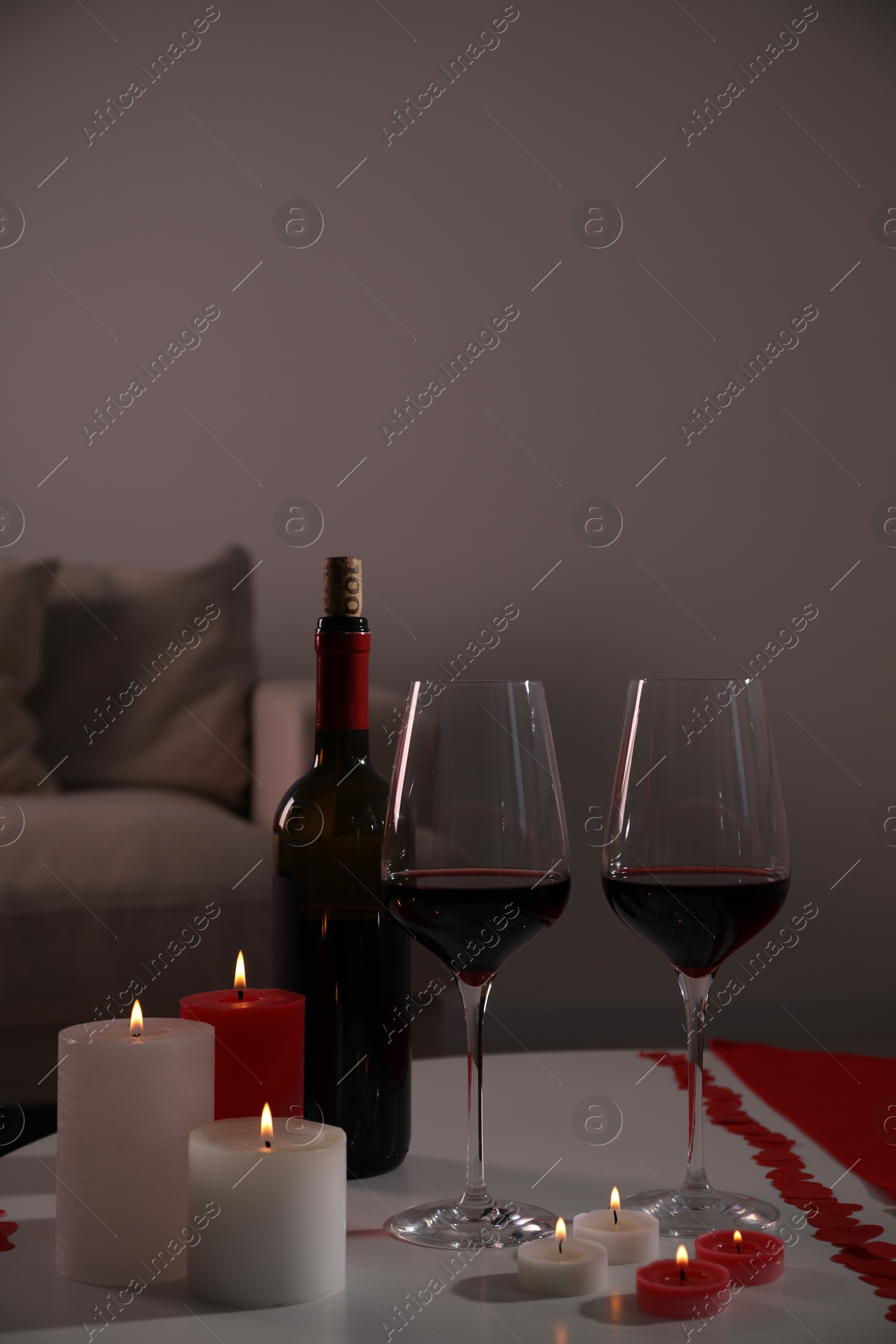 Photo of Burning candles, wine and paper hearts on table indoors