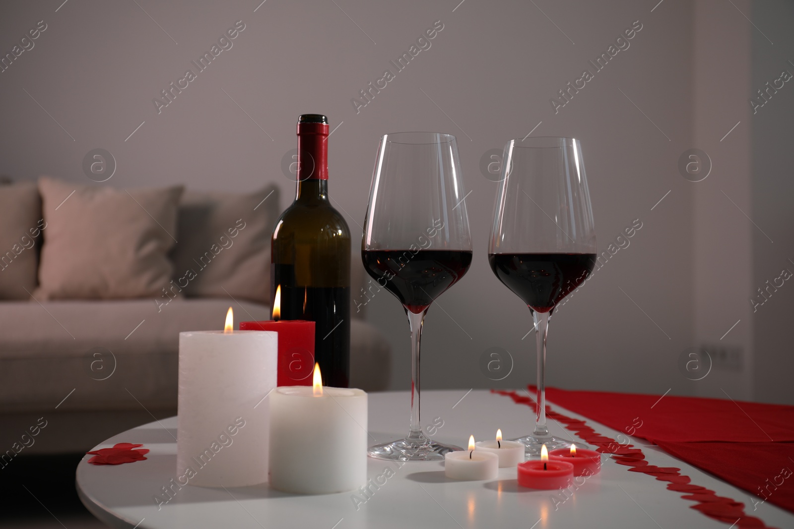 Photo of Burning candles, wine and paper hearts on table indoors