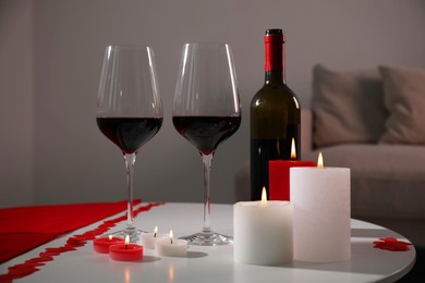 Photo of Burning candles, wine and paper hearts on table indoors