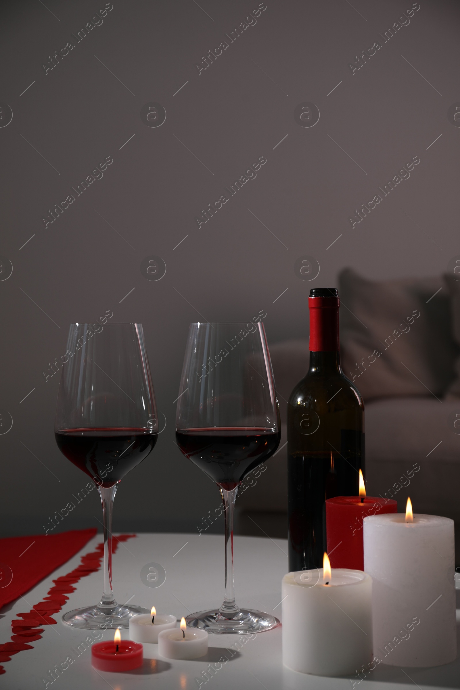 Photo of Burning candles, wine and paper hearts on table indoors