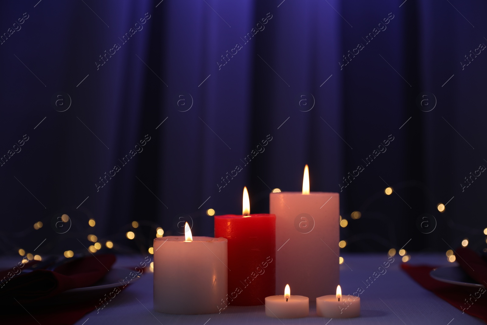 Photo of Burning candles on table against blurred lights