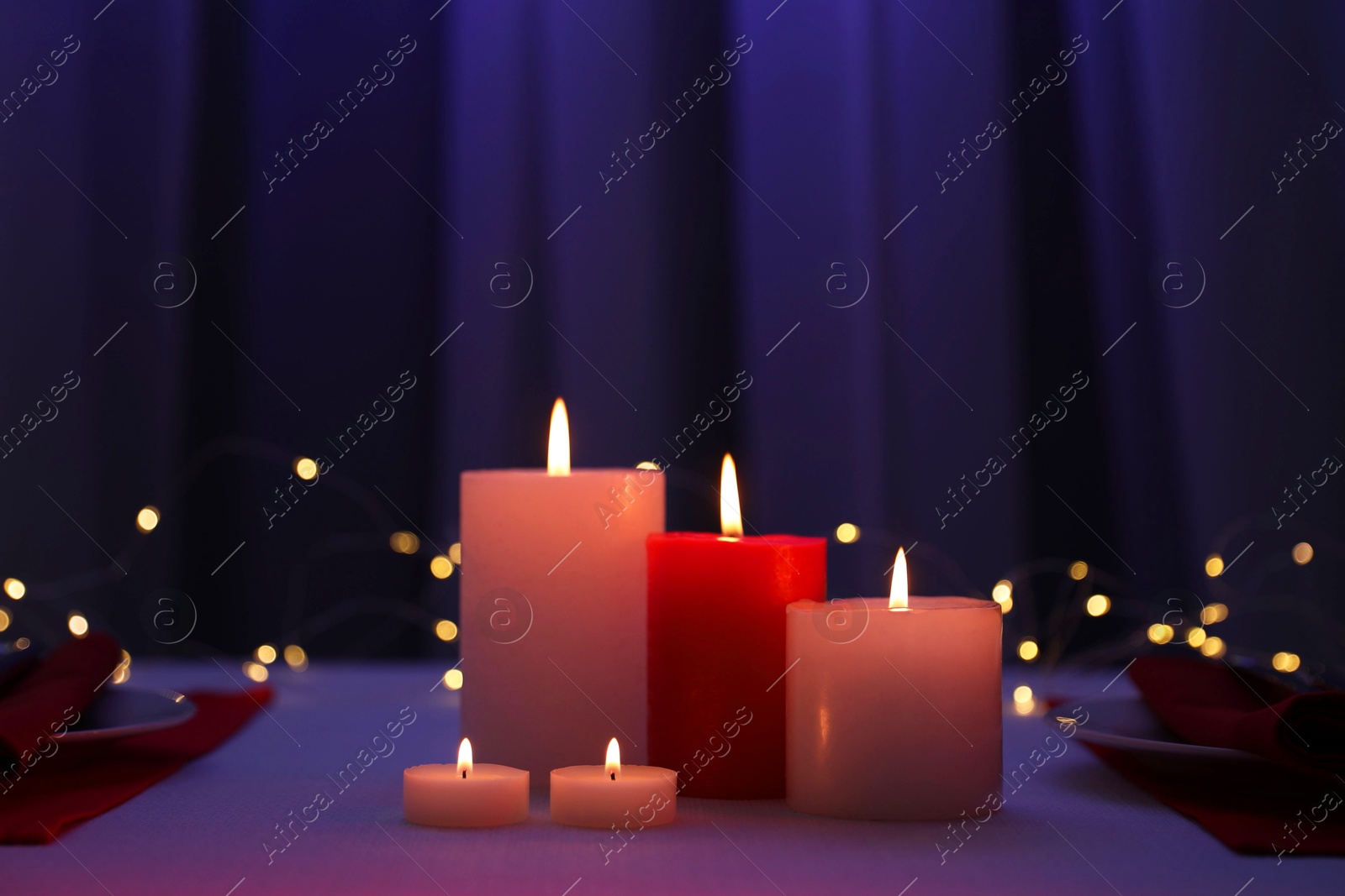 Photo of Burning candles on table against blurred lights