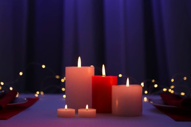 Photo of Burning candles on table against blurred lights