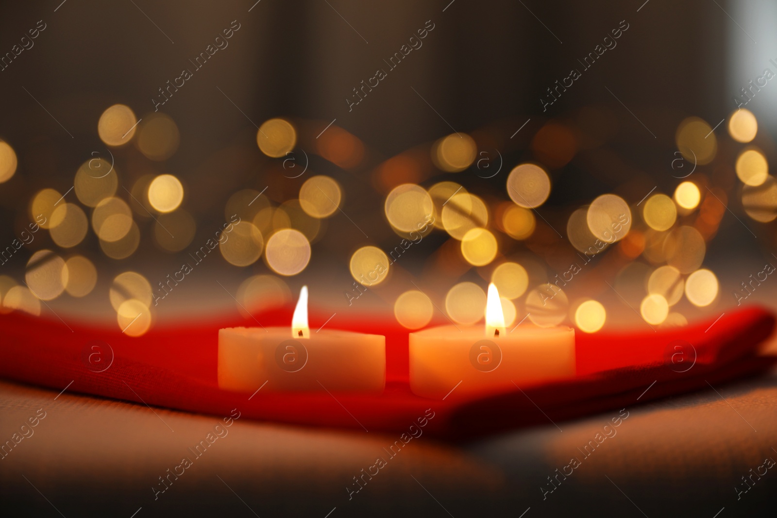 Photo of Burning candles on table against blurred lights, closeup