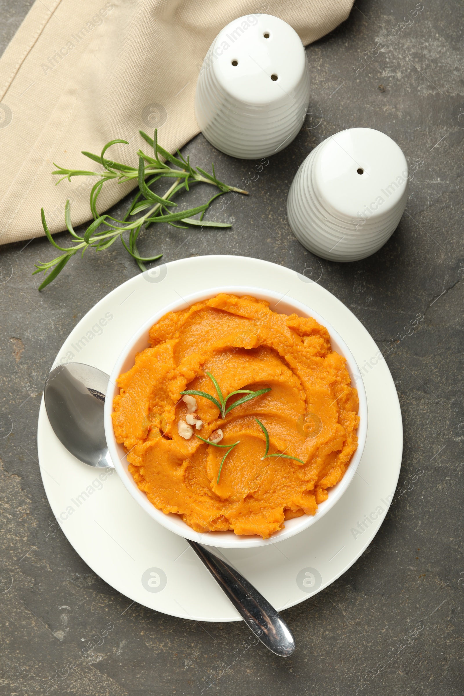 Photo of Delicious mashed sweet potatoes served on gray textured table, flat lay