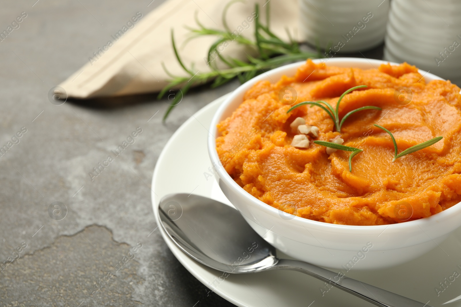 Photo of Delicious mashed sweet potatoes served on gray textured table, closeup