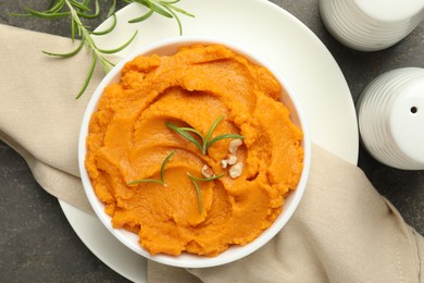 Photo of Delicious mashed sweet potatoes in bowl and spices on gray textured table, flat lay