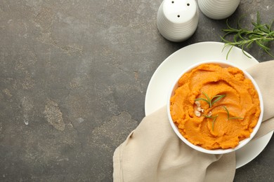 Delicious mashed sweet potatoes in bowl and spices on gray textured table, flat lay. Space for text