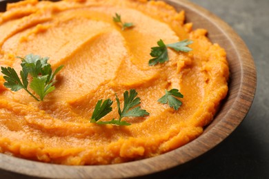 Photo of Delicious mashed sweet potatoes with parsley in bowl on table, closeup