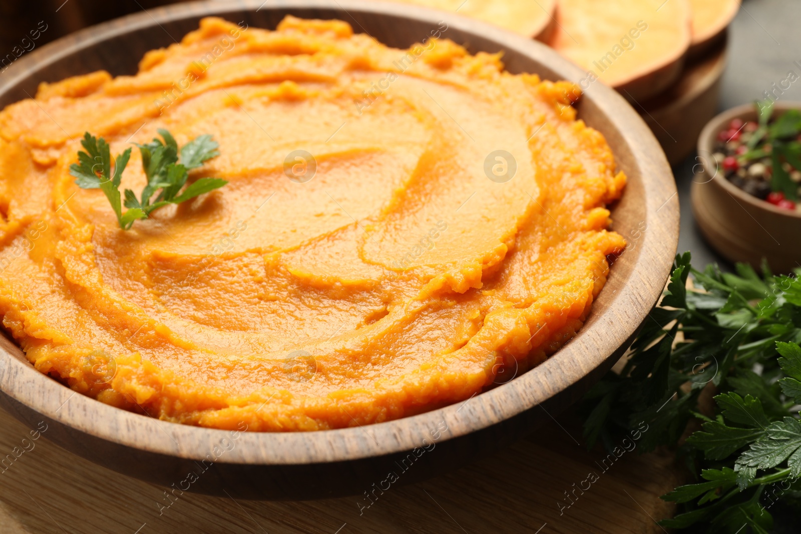 Photo of Delicious mashed sweet potatoes with parsley in bowl on table, closeup