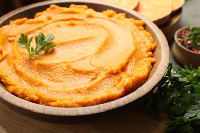 Photo of Delicious mashed sweet potatoes with parsley in bowl on table, closeup