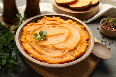 Photo of Delicious mashed sweet potatoes in bowl and spices on gray textured table, closeup