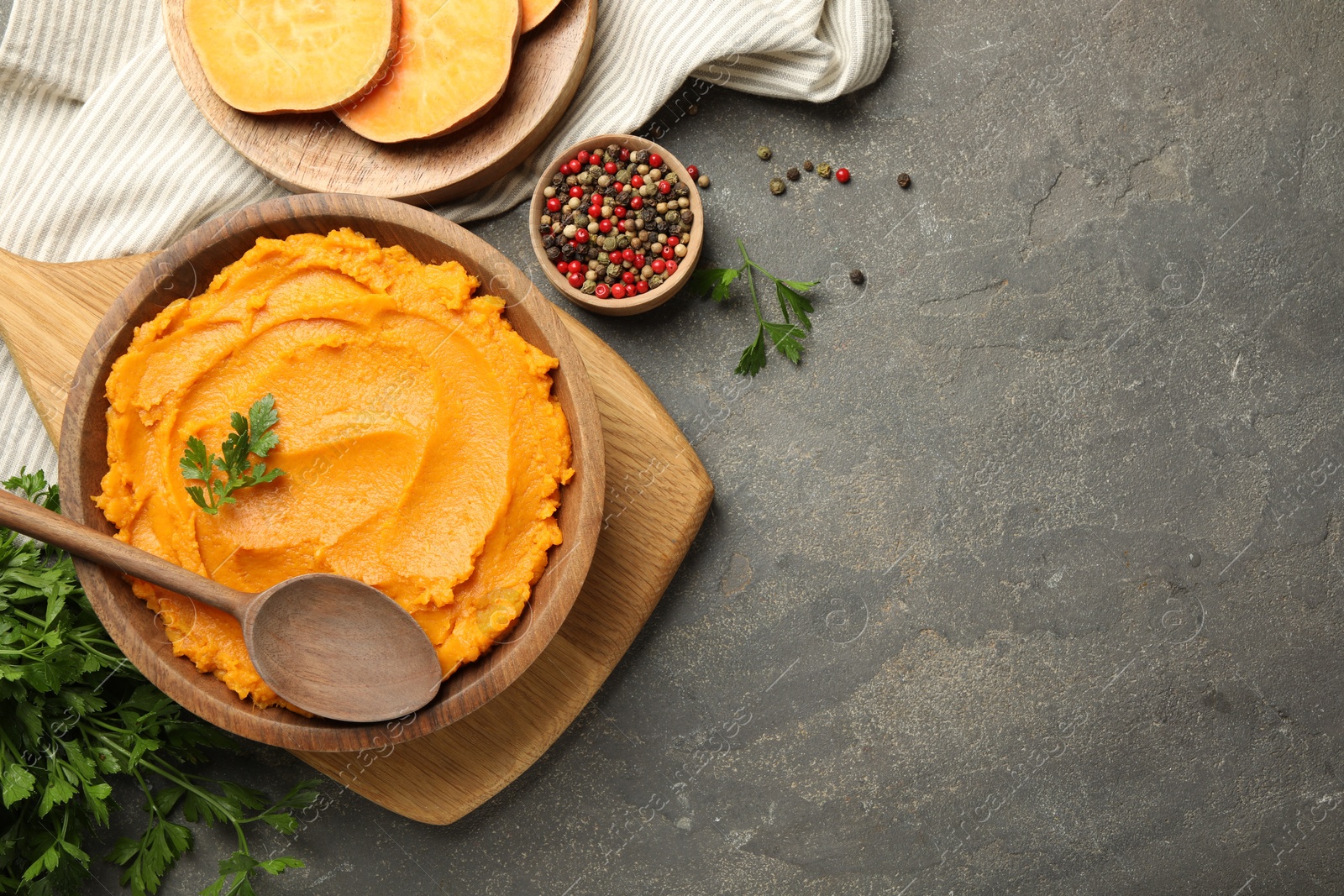 Photo of Delicious mashed sweet potatoes served on gray textured table, flat lay. Space for text