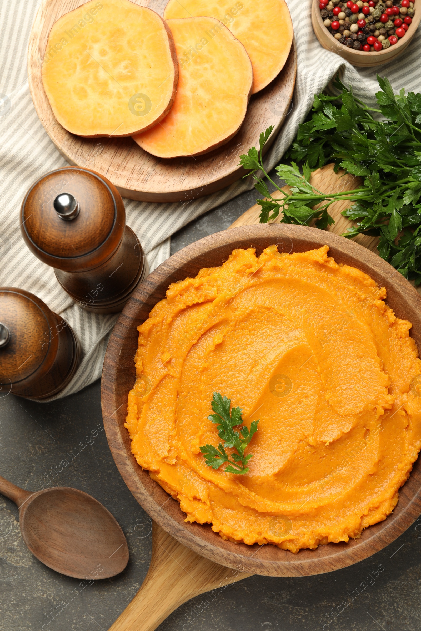 Photo of Delicious mashed sweet potatoes served on gray textured table, flat lay