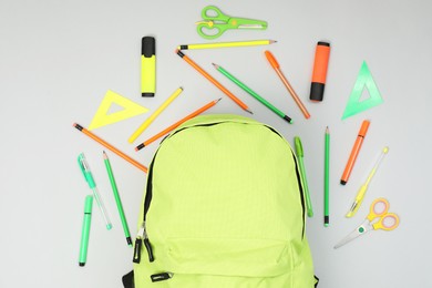 Photo of Backpack and different school supplies on light gray background, flat lay