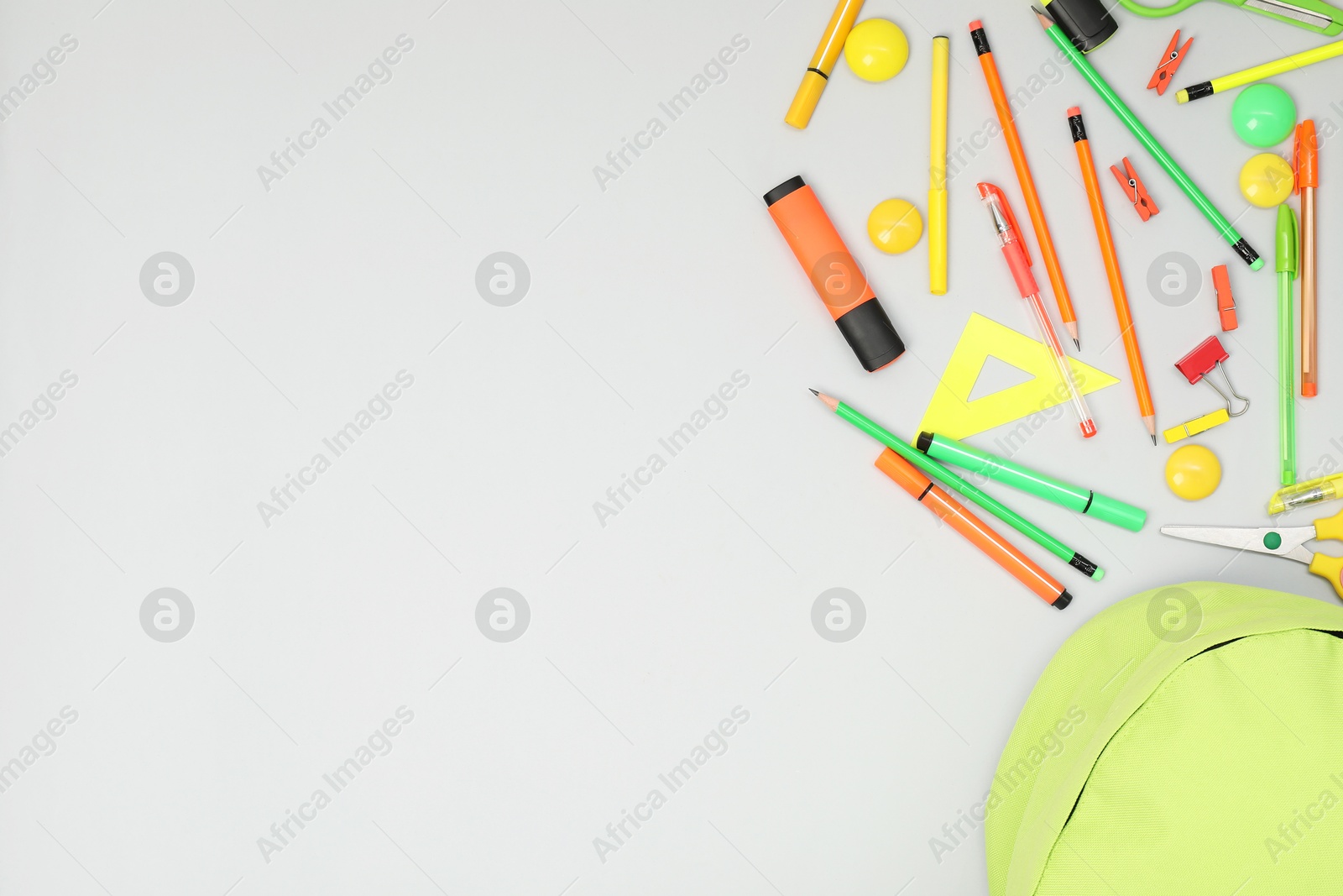 Photo of Backpack and different school supplies on light gray background, flat lay. Space for text